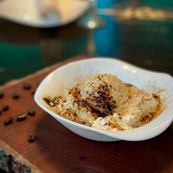 Aman's Artisan Indian Cuisine's coffee ice cream dessert with chocolate drizzle and coffee beans.