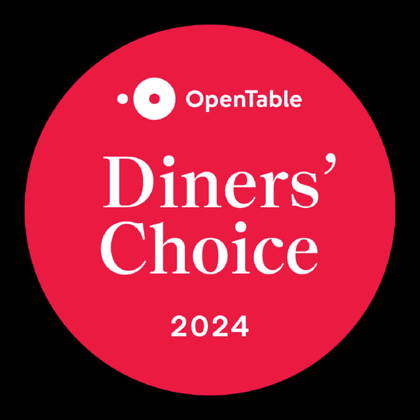 A red circular OpenTable Diners' Choice 2024 award logo for Aman's Artisan Indian Cuisine.