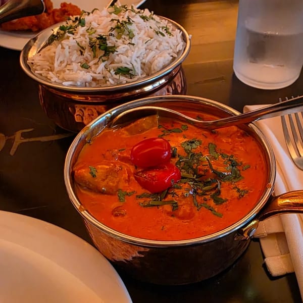 Aman's Artisan Indian Cuisine's butter chicken with cherry tomatoes and cilantro, alongside basmati rice.