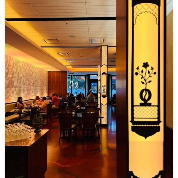 Aman's Artisan Indian Cuisine dining room with patrons seated at tables and decorative Indian-inspired pillars.
